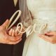 Casal segurando letras "love" é a identidade visual para casamento