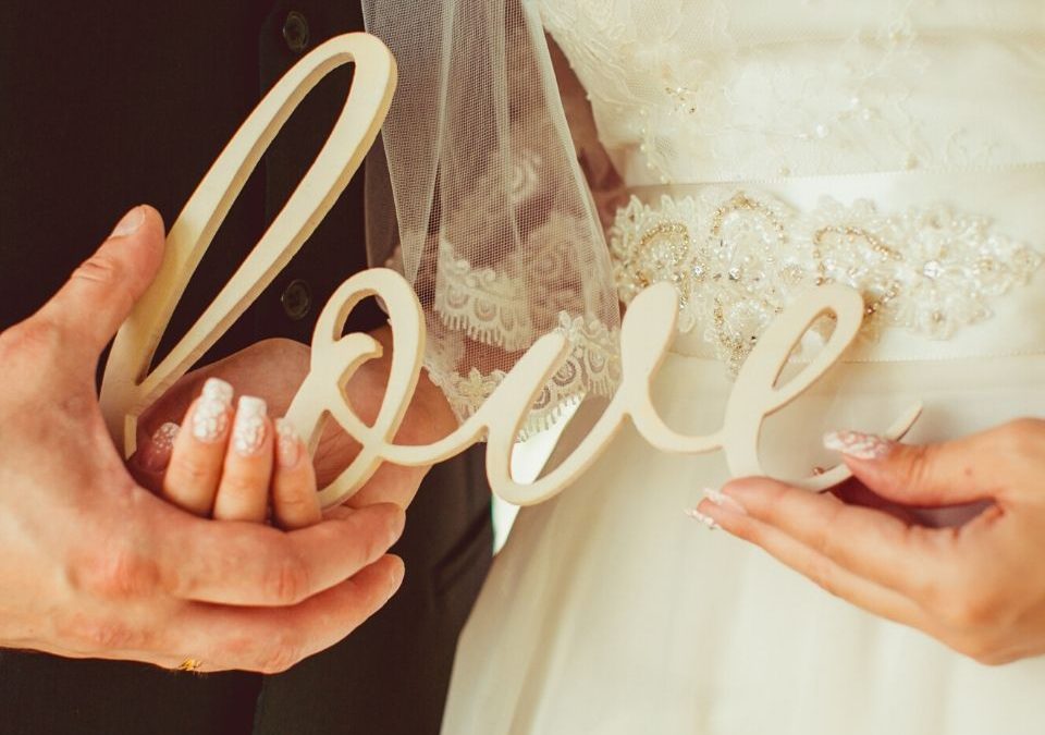 Casal segurando letras "love" é a identidade visual para casamento